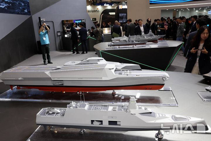 [부산=뉴시스] 하경민 기자 = '국제해양방위산업전 2025(MADEX)'가 개막한 28일 부산 해운대구 벡스코 제1전시장을 찾은 관람객들이 HD현대중공업 부스에서 미래형 무인전력모함 등 각종 해군 함정 모형을 살펴보고 있다. 2025.05.28. yulnetphoto@newsis.com