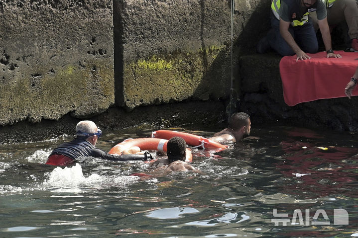 [엘이에로=AP/뉴시스] 28일(현지 시간) 스페인 카나리아제도 엘이에로 항구 인근에서 전복된 이민자 보트의 생존자들이 구조되고 있다. 현지 당국은 서아프리카 기니에서 약 180명을 태우고 출발한 이 보트가 항구에 접근하던 중 전복돼 5세 여아 2명 포함 최소 7명의 여성이 숨졌다고 밝혔다. 현지 경찰은 승선자들이 보트 한쪽으로 몰리면서 사고가 일어난 것으로 보인다고 전했다. 2025.05.29.