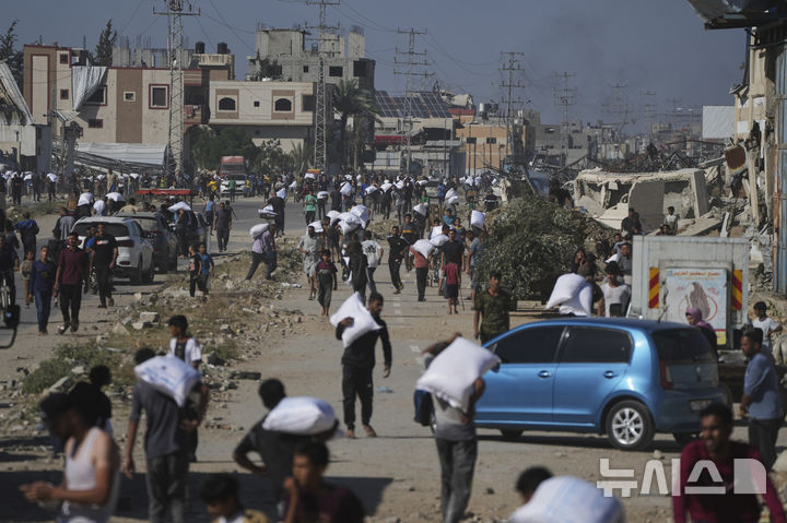 [가자지구=AP/뉴시스] 28일(현지 시간) 가자지구 자와이다에 위치한 유엔 세계식량계획 창고를 습격한 팔레스타인인들이 밀가루를 들고 이동하고 있다. 2025.05.29.