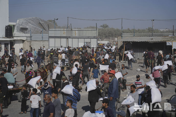 [가자지구=AP/뉴시스] 28일(현지 시간) 가자지구 자와이다에 위치한 유엔 세계식량계획 창고를 습격한 팔레스타인인들이 밀가루를 들고 이동하고 있다. 2025.05.29.
