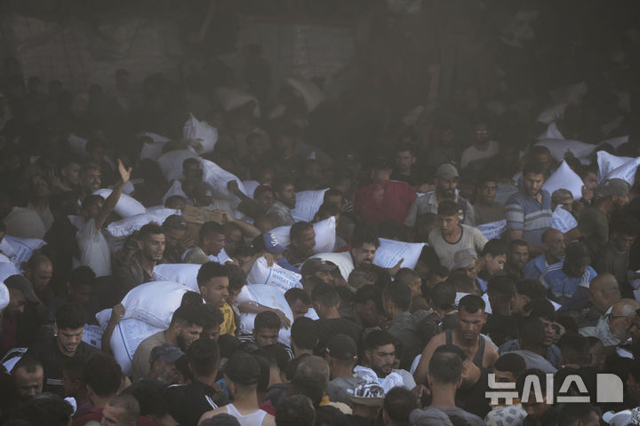 [가자지구=AP/뉴시스] 28일(현지 시간) 가자지구 자와이다에 위치한 유엔 세계식량계획 창고를 습격한 팔레스타인인들이 밀가루를 들고 이동하고 있다. 2025.05.29.