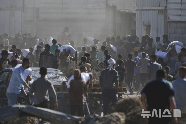 [가자지구=AP/뉴시스] 28일(현지 시간) 가자지구 자와이다에 위치한 유엔 세계식량계획 창고를 습격한 팔레스타인인들이 밀가루를 들고 이동하고 있다. 2025.05.29.