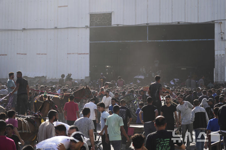 [가자지구=AP/뉴시스] 28일(현지 시간) 가자지구 자와이다에 위치한 유엔 세계식량계획 창고를 습격한 팔레스타인인들이 밀가루를 들고 이동하고 있다. 2025.05.29.
