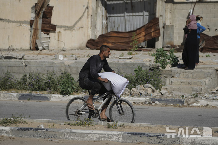 [가자지구=AP/뉴시스] 28일(현지 시간) 가자지구 자와이다에 위치한 유엔 세계식량계획 창고를 습격한 팔레스타인인들이 밀가루를 들고 이동하고 있다. 2025.05.29.