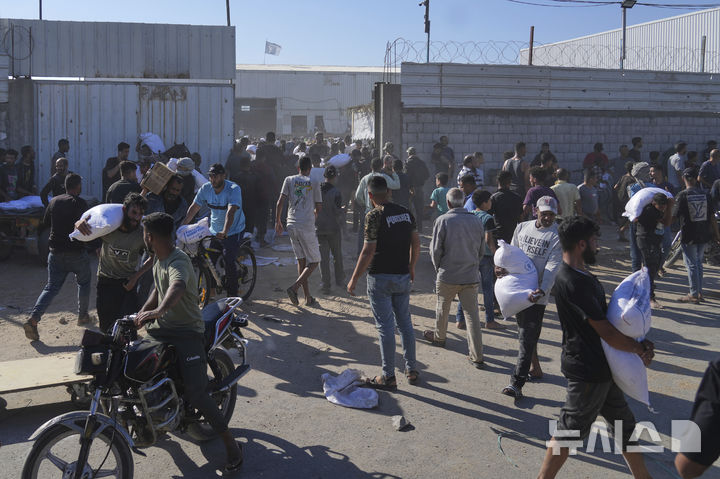 [가자지구=AP/뉴시스] 28일(현지 시간) 가자지구 자와이다에 위치한 유엔 세계식량계획 창고를 습격한 팔레스타인인들이 밀가루를 들고 이동하고 있다. 2025.05.29.