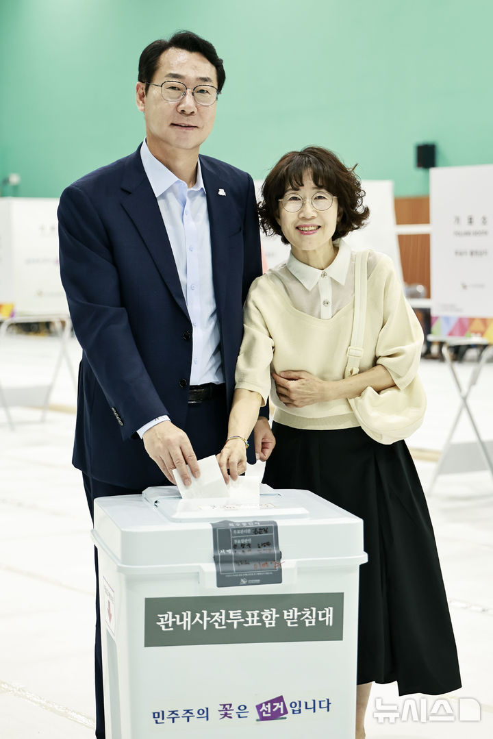 [화성=뉴시스]정명근 화성시장이 29일 배우자 이선희 여사와 봉담2지구 다목적체육관에 마련된 봉담읍사전투표소에서 기표한후 투표용지를 투표함에 넣고 있다.(사진=화성시 제공)2025.05.29.photo@newsis.com