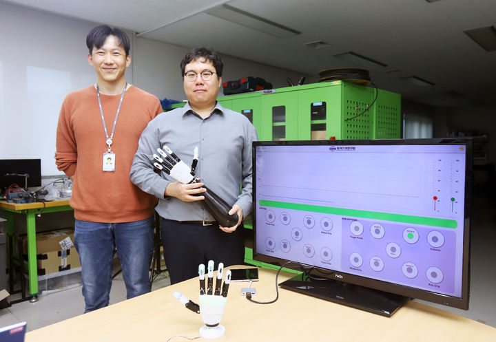 [대전=뉴시스] 기계연구원이 단순한 제어로 고효율·고안정성 파지 기능을 구현할 수 있는 로봇의수 기술을 개발했다. 기계연 신민기(오른쪽) 선임연구원과 안보현 선임기술원이 개발한 로봇의수를 들어보이고 있다.(사진=기계연구원 제공) *재판매 및 DB 금지