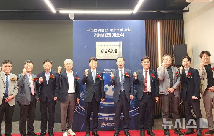 [창원=뉴시스]29일 경남 창원스마트혁신지원센터에서 열린 제조 산업과 인공지능 기술 접목·확산 거점기관 '경남 AX랩' 개소식 참석자들이 현판을 제막한 후 기념촬영하고 있다.(사진=경남도 제공) 2025.05.29. photo@newsis.com