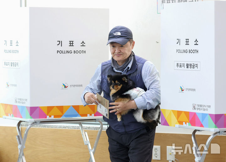 [서울=뉴시스] 김진아 기자 = 제21대 대통령선거 사전투표가 시작된 29일 서울 중구 중림동주민센터에 마련된 사전투표소에서 한 유권자가 강아지와 투표를 하고 있다. 2025.05.29. bluesoda@newsis.com