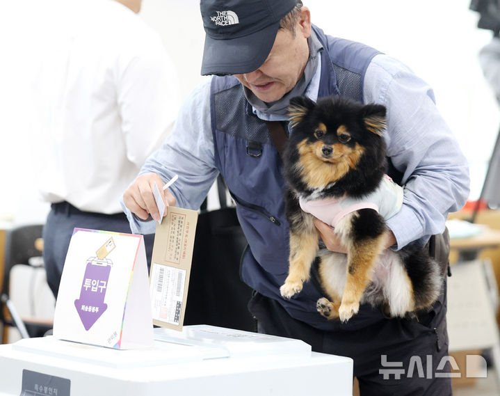 [서울=뉴시스] 김진아 기자 = 제21대 대통령선거 사전투표가 시작된 29일 서울 중구 중림동주민센터에 마련된 사전투표소에서 한 유권자가 강아지와 투표를 하고 있다. 2025.05.29. bluesoda@newsis.com