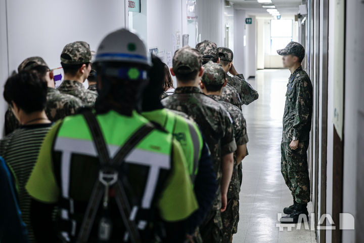 [서울=뉴시스] 정병혁 기자 = 제21대 대통령선거 사전투표 첫 날인 29일 서울 서초구 반포프라자상가 재건축사업추진단 사무실에 설치된 사전투표소를 찾은 군인과 유권자들이 투표를 하기 위해 줄 서 있다. 2025.05.29. jhope@newsis.com