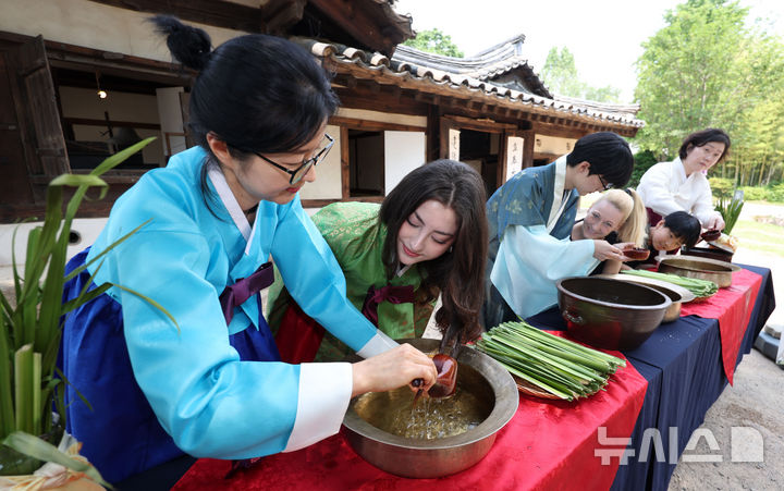 [서울=뉴시스] 김선웅 기자 = 단오(음력 5월 5일)를 이틀 앞둔 29일 서울 종로구 국립민속박물관 오촌댁 앞마당에서 열린 단오 세시행사에서 방문객들이 창포물 머리감기 체험을 하고 있다. 2025.05.29. mangusta@newsis.com