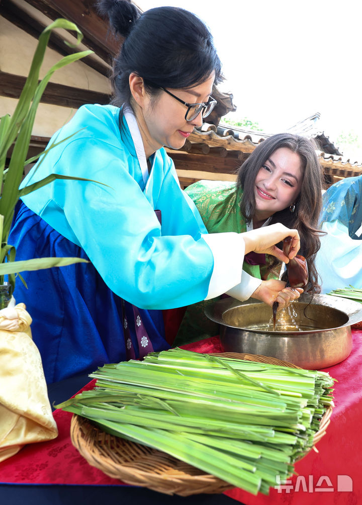 [서울=뉴시스] 김선웅 기자 = 단오(음력 5월 5일)를 이틀 앞둔 29일 서울 종로구 국립민속박물관 오촌댁 앞마당에서 열린 단오 세시행사에서 외국인 관광객이 창포물 머리감기 체험을 하고 있다. 2025.05.29. mangusta@newsis.com