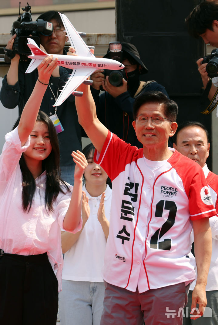 [충주=뉴시스] 고승민 기자 = 김문수 국민의힘 대선 후보가 30일 충북 충주 젊음의거리에서 유세를 하기 전 청년 참가자에게 '항공물류 허브공항' 메시지가 적힌 모형 비행기를 들어 보이고 있다. 2025.05.30. kkssmm99@newsis.com