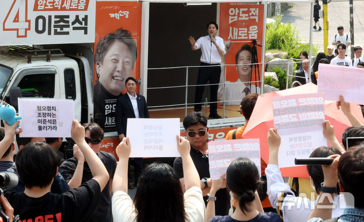[서울=뉴시스] 추상철 기자 = 30일 오후 서울 동작구 중앙대학교 후문에서 대학생들이 유세를 펼치는 이준석 개혁신당 대선후보를 향해 혐오 발언 규탄 피켓을 들어 보이고 있다. 2025.05.30. scchoo@newsis.com