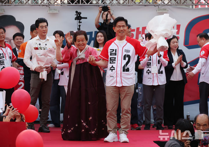 [포항=뉴시스] 고승민 기자 = 김문수 국민의힘 대선 후보가 31일 경북 포항 북포항우체국 앞에서 유세를 하기 전 포항 시민으로부터 꽃다발을 받으며 기념촬영하고 있다. 2025.05.31. kkssmm99@newsis.com