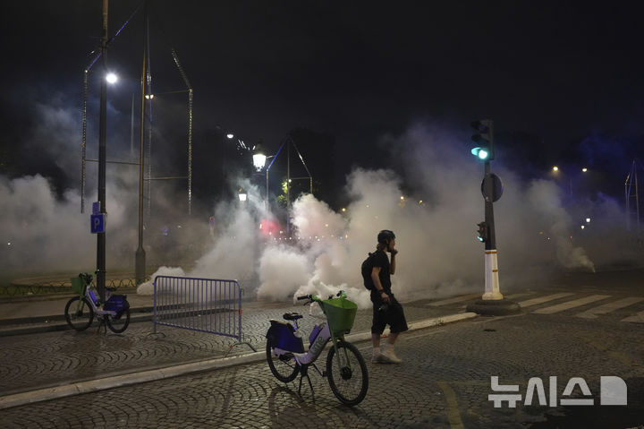 A man walks past tear gas during incidents after the Champions League final soccer match between Paris Saint-Germain and Inter Milan, Sunday, June 1, 2025 in Paris. (AP Photo/Aurelien Morissard)