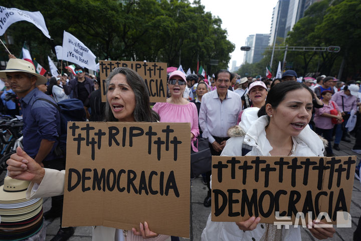 [멕시코시티=AP/뉴시스] 멕시코 사상 처음으로 사법부 선거가 실시된 1일(현지 시간) 수도 멕시코시티에서 시위대가 '영면하소서, 민주주의'라고 적힌 팻말을 들고 구호를 외치고 있다. 2025.06.02.