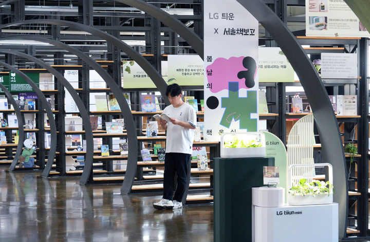 [서울=뉴시스]LG전자가 내달 13일까지 서울 송파구에 있는 ‘서울책보고’에서 식물생활가전 ‘LG 틔운 미니’를 활용해 식물과 독서가 만나는 특별한 체험 공간을 선보인다. 사진은 LG 틔운 미니를 활용해 조성된 내부 서가와 열람실 공간에서 독서하며 다양한 식물을 감상하는 모습. photo@newsis.com *재판매 및 DB 금지