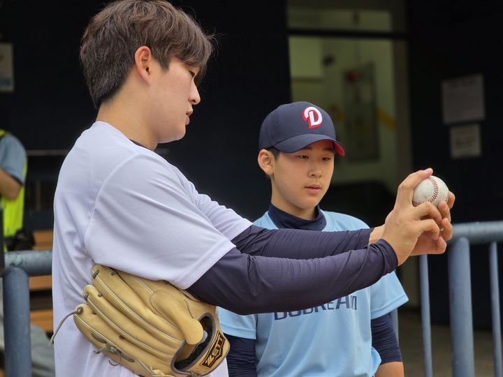[서울=뉴시스]두산 베어스 투수 김택연 2일 서울 잠실구장에서 열린 야구클리닉 '두드림'에 참가한 유소년 선수에게 그립을 알려주고 있다. (사진=&nbsp; 한국프로야구선수협회 제공) 2025.06.02. photo@newsis.com *재판매 및 DB 금지