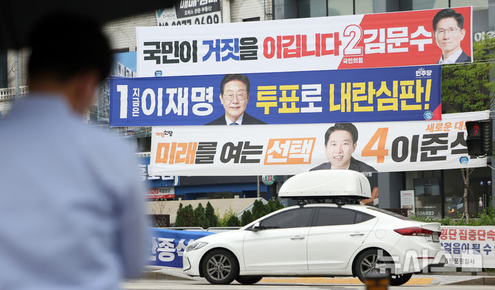 [서울=뉴시스] 김선웅 기자 = 지난 2일 서울 영등포구 한 교차로에서 시민들이 대선 후보 현수막 앞을 지나고 있다. 2025.06.02. mangusta@newsis.com