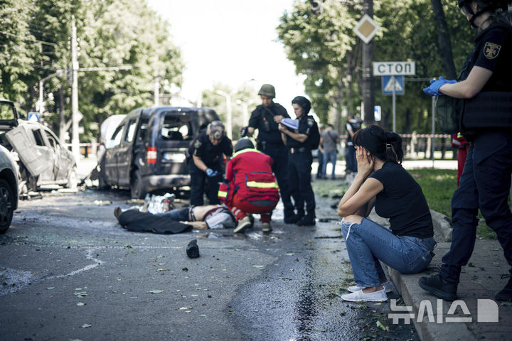 [수미=AP/뉴시스] 6월 3일 러시아의 공습을 받은 우크라이나 수미에서 구조대가 희생자 시신을 수습하는 동안 한 여성이 충격과 슬픔에 빠진 채 길 가에 앉아 있다. 러시아군의 공습으로 최소 3명이 숨지고 20명이 부상한 것으로 전해졌다. 2025.06.04.