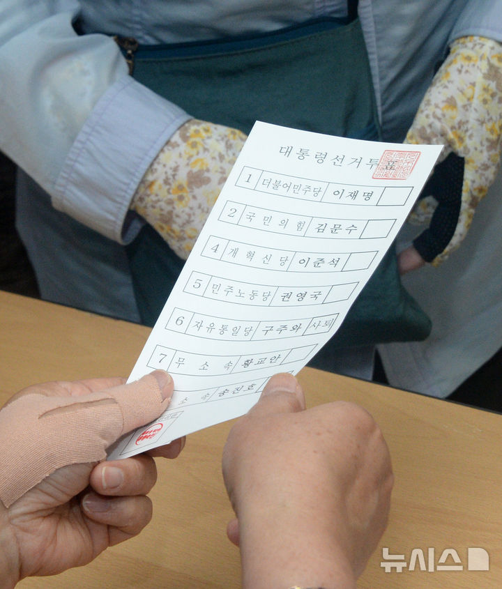 [전주=뉴시스] 김얼 기자 = 제21대 대통령선거일인 3일 전북 전주시 완산구 평화1동 제2투표소(전주남중학교)를 찾은 한 시민이 투표용지를 받고 있다. 2025.06.03. pmkeul@newsis.com