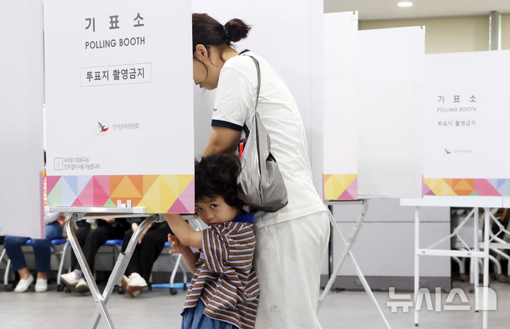 [부산=뉴시스] 하경민 기자 = 제21대 대통령 선거일인 3일 부산 연제구청에 마련된 연산제2동 제3투표소에서 한 어린이가 부모와 함께 기표소에 들어가 주위를 둘러보고 있다. 2025.06.03. yulnetphoto@newsis.com