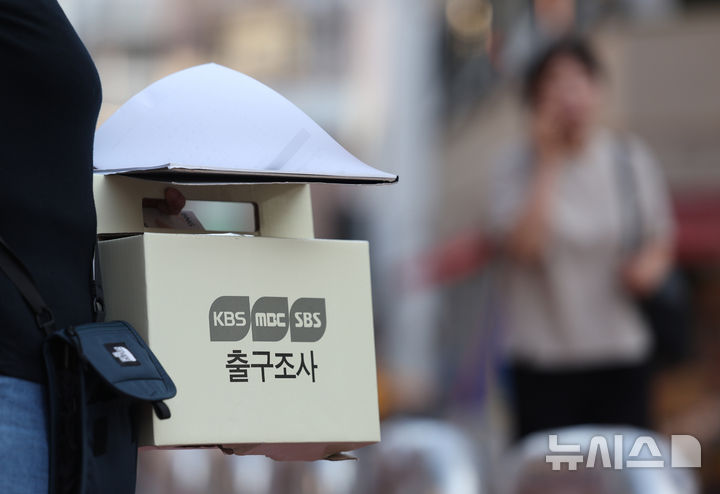 [서울=뉴시스] 김진아 기자 = 제21대 대통령 선거일인 3일 서울 영등포구 당산1동주민센터에 마련된 투표소 앞에서 방송사 출구조사원이 출구조사를 하고 있다. 2025.06.03. bluesoda@newsis.com