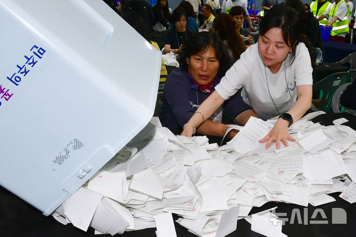 [광주=뉴시스] 이현행 기자 = 제21대 대통령 선거가 치러진 3일 오후 광주 서구 빛고을체육관에 마련된 광주시선관위의 개표소에서 개표사무원들이 쏟아지는 투표용지를 받고 있다. 2025.06.03. lhh@newsis.com