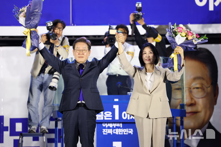 [서울=뉴시스] 조성우 기자 = 이재명 대통령과 김혜경 여사가 4일 오전 서울 여의도 국회 앞에서 열린 국민 개표방송 행사에서 꽃다발을 받은 뒤 시민들을 향해 인사하고 있다. 2025.06.04. xconfind@newsis.com