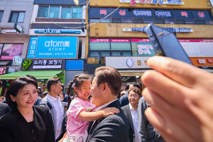 [서울=뉴시스] 이재명 대통령과 김혜경 여사가 6일 서울 동작구 남성시장을 방문해 한 아이를 안아주고 있다. (사진=대통령실 제공) 2025.06.06. photo@newsis.com *재판매 및 DB 금지