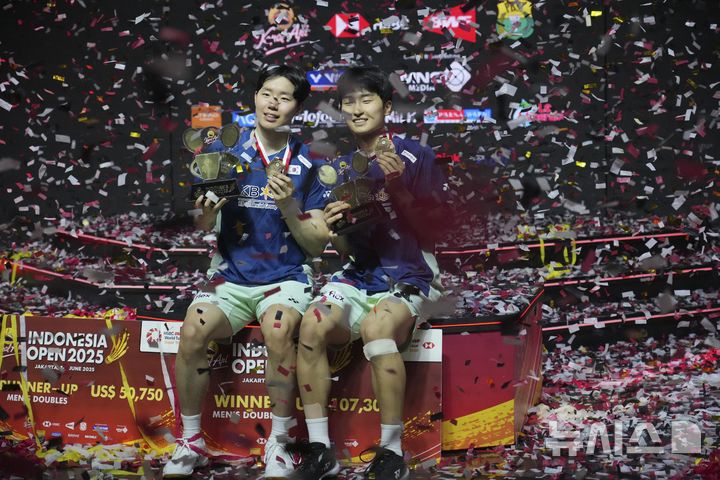 [자카르타=AP/뉴시스] 김원호(오른쪽)와 서승재가 8일(현지 시간) 인도네시아 자카르타 이스토라 스타디움에서 열린 2025 세계배드민턴연맹(BWF) 월드투어 슈퍼 1000 인도네시아오픈 남자복식 정상에 올라 금메달과 트로피를 들고 포즈를 취하고 있다. 김원호-서승재는 결승에서 사바르 카르야만 구타마-모 레자 파흘레비 이스파하니 조(인도네시아)에 2-1(18-21 21-19 21-12)로 역전승을 거두고 우승을 차지했다. 2025.06.09.