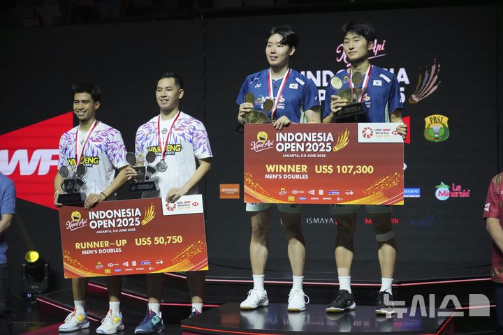 [자카르타=AP/뉴시스] 김원호(오른쪽)와 서승재가 8일(현지 시간) 인도네시아 자카르타 이스토라 스타디움에서 열린 2025 세계배드민턴연맹(BWF) 월드투어 슈퍼 1000 인도네시아오픈 남자복식 정상에 올라 시상대에서 기념 촬영하고 있다. 김원호-서승재는 결승에서 사바르 카르야만 구타마-모 레자 파흘레비 이스파하니 조(인도네시아)에 2-1(18-21 21-19 21-12)로 역전승을 거두고 우승을 차지했다. 2025.06.09.