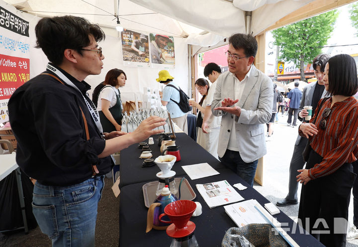 [서울=뉴시스] 김진아 기자 = 오승록 노원구청장이 8일 서울 노원구 공릉역 일대에서 열린 '제3회 경춘선 공릉숲길 커피축제'에서 카메룬 블루마운틴 공정무역커피에 대한 설명을 듣고 있다.&nbsp;&nbsp; '커피 여행'을 주제로 열린 이번 축제에서는 케냐, 과테말라, 엘살바도르 등 세계 20여 개국의 커피를 맛보고 각국의 고유한 커피 문화도 체험해볼 수 있다. 2025.06.08. bluesoda@newsis.com