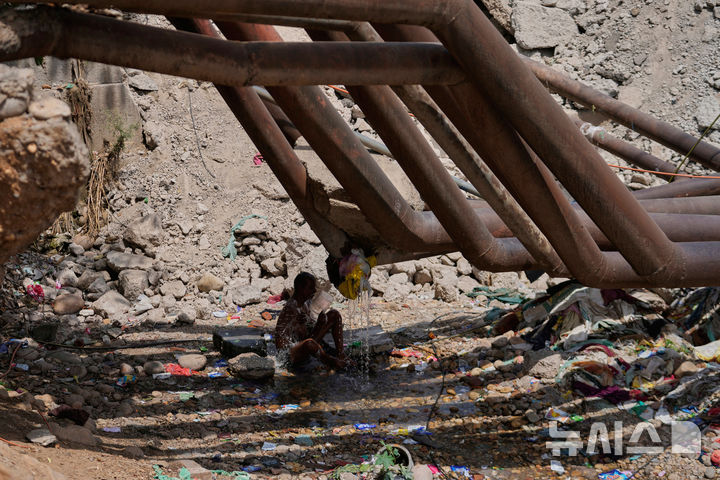 <font style="vertical-align: inherit;"><font style="vertical-align: inherit;">[인도=AP/뉴시스] 10일(현지 시간) 인도 잠무에서 한 남성이 파이프관에서 새는 물로 더위를 식히고 있다. 2025.06.12.</font></font>