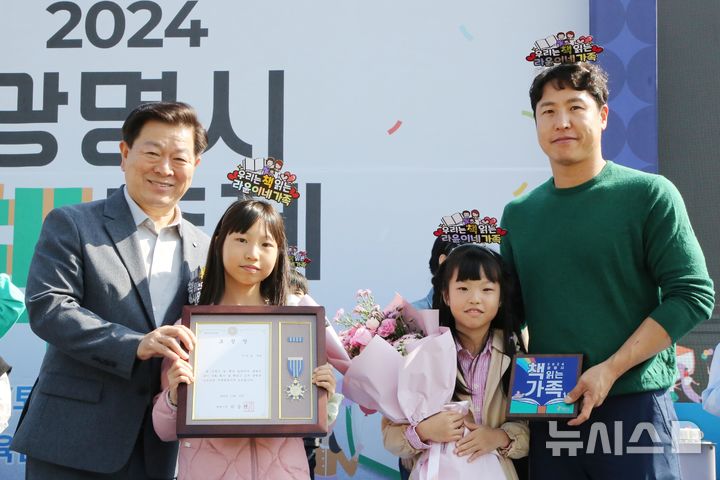 [광명=뉴시스]박승원 광명시장(사진 왼쪽 첫 번째)이 2024년 10월 광명시민체육관 잔디광장에서 열린 '2024 광명시 책축제'에서 독서문화 실천 가족에게 표창장을 수여하고 기념촬영을 하고 있다.(사진=광명시 제공)2025.06.11.photo@newsis.com