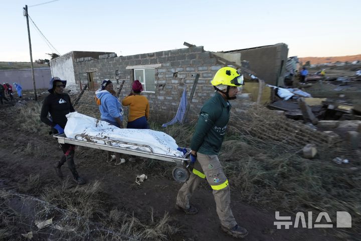 [음타타( 남아프리카)= AP/뉴시스]  남아프리카 동부에서 계속되는 홍수로 사망자가 발생한 음타타 지역에서 6월 12일 구조대가 사망자 시신을 수습해서 옮기고 있다.  2025. 06. 25.  