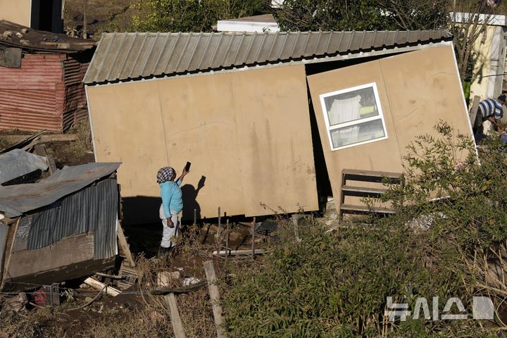 [AP/뉴시스] [음타타( 남아프리카)= AP/뉴시스]  남아프리카 동부에서 계속되는 홍수로 사망자가 발생한 음타타 지역에서 6월 12일 한 여성주민이 물이 빠진 지역에서 홍수로 파괴된 집을 살펴보고 있다. 2025.06. 25.  