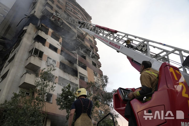 [테헤란=AP/뉴시스] 13일(현지 시간) 이란 테헤란 북부의 주거 단지 폭발 현장에서 소방관들이 진화 작업을 하고 있다. 이스라엘방위군(IDF)은 이날 새벽 이스라엘이 이란의 핵·군 시설에 대한 선제타격을 개시했다고 성명을 통해 밝혔다. 2025.06.13.
