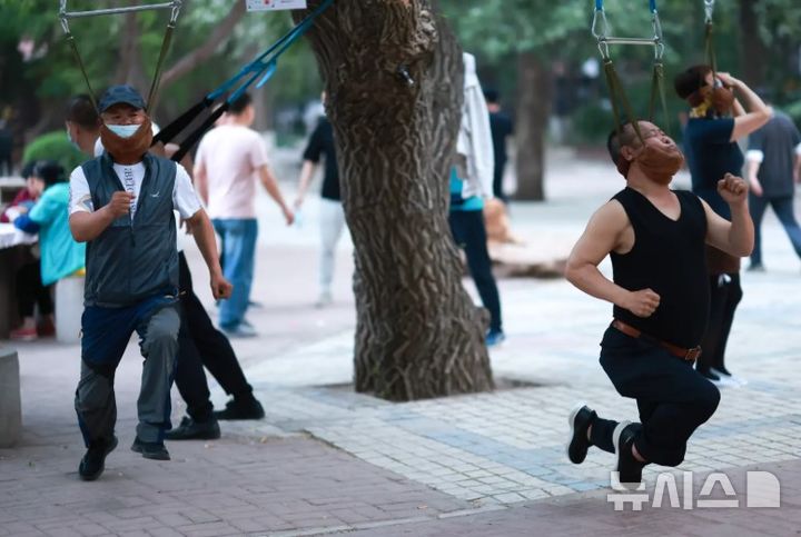 [뉴시스]중국 선양의 노년층 사이에서 밴드에 턱을 걸어 그네를 타는 듯한 수면 요법이 유행처럼 번지고 있다. (사진=뉴욕포스트) 