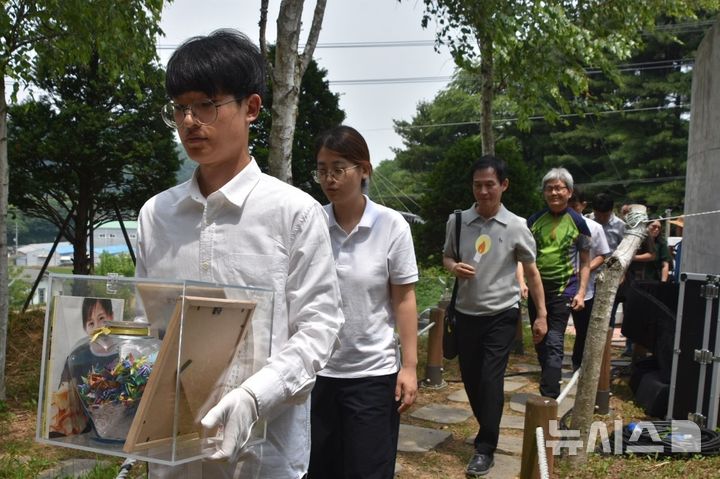 [양주=뉴시스] 고(故) 신효순·심미선양의 23주기 추모제가 13일 오전 경기 양주시 효순미선평화공원에서 열린 가운데 참가자들이 효순양의 유품을 들고 기록관 부지로 향하고 있다. (사진=효순미선평화공원사업위원회 제공) 2025.06.13. photo@newsis.com 