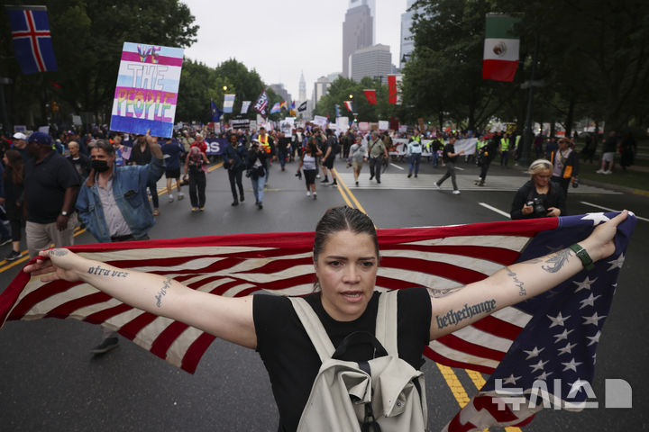 [필라델피아=AP/뉴시스] 14일(현지 시간) 미 펜실베이니아주 필라델피아에서 ‘노 킹스(No Kings)’ 시위 참가자들이 성조기와 각종 손팻말을 들고 행진하고 있다. 미 전역에서 트럼프 대통령의 권위주의적 국정운영을 비판하는 '노 킹스(No Kings)' 시위가 이어지고 있다. 2025.06.15.