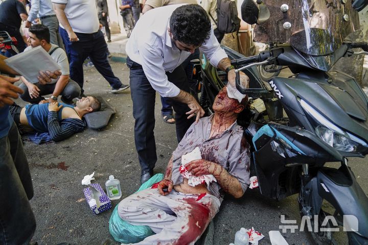 [테헤란=AP/뉴시스]이스라엘과 이란의 충돌이 계속되고 있는 가운데 지난 15일 이란 수도 테헤란의 도심에 이스라엘의 공습이 있은 후 부상당한 한 남자가 거리에서 치료를 받고 있는 모습.