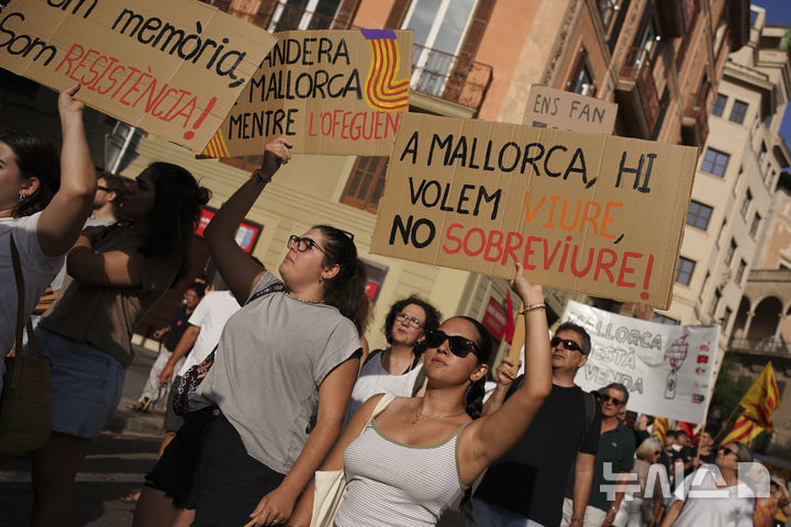 <font style="vertical-align: inherit;"><font style="vertical-align: inherit;">[마요르카=AP/뉴시스] 15일(현지 시간) 스페인 마요르카에서 오버투어리즘(과잉 관광)에 반대하는 시위가 열린 가운데 한 참가자가 "마요르카에서 우리는 살아남고 싶지 않고 살고 싶다"고 적은 피켓을 들고 있다. 2025.06.16.</font></font>