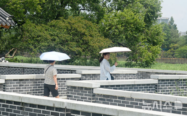 [전주=뉴시스] 김얼 기자 = 16일 전북 전주시 전주덕진공원을 찾은 시민들이 양산으로 햇빛을 피하며 산책을 즐기고 있다. 2025.06.16. pmkeul@newsis.com