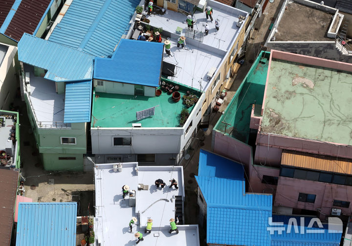 [부산=뉴시스] 하경민 기자 = 부산시자원봉사센터와 7개 기업·기관, 대학생 자원봉사자 등 130여 명이 17일 부산 남구 문현2동 일대 주택 20여 곳의 옥상에서 쿨루프(Cool Roof) 열차단 페인트를 도포하는 봉사활동을 하고 있다.쿨루프는 태양열 반사 및 열 차단 효과가 있는 친환경 도료를 주택 지붕 및 옥상에 도포해 실내온도를 효과적으로 낮추는 기술이다. 2025.06.17. yulnetphoto@newsis.com