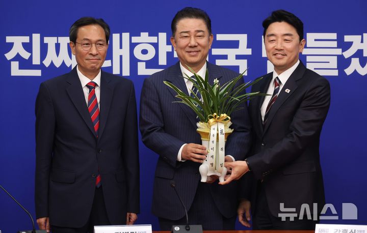 [서울=뉴시스] 조성봉 기자 = 김병기(가운데) 더불어민주당 당대표 직무대행 겸 원내대표가 17일 서울 여의도 국회에예방온 강훈식 대통령실 비서실장과 우상호(왼쪽) 정무수석에게 이재명 대통령의 축하 난을 전달받고 기념촬영을 하고 있다. 2025.06.17. suncho21@newsis.com