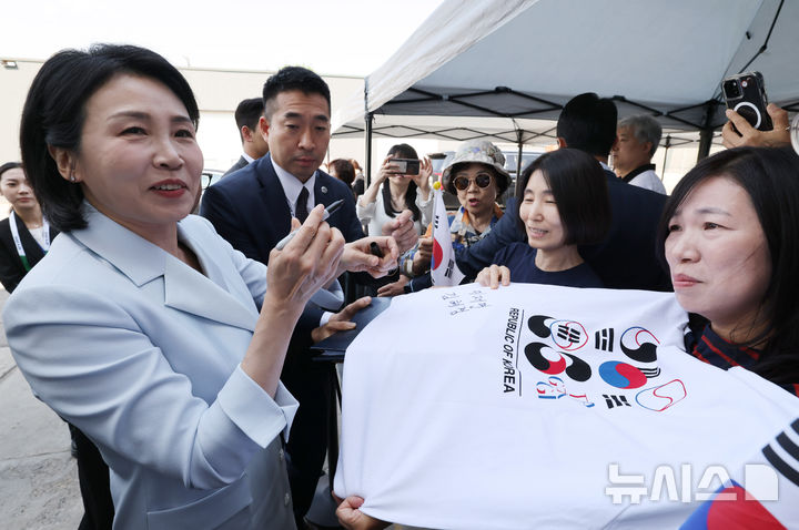 [캘거리=뉴시스] 최진석 기자 = 이재명 대통령 부인 김혜경 여사가 17일(현지 시간) 캐나다 앨버타주 캘거리 한인회관에서 열린 캐나다 서부 동포사회와의 대화를 나누기 전 인사하며 티셔츠에 싸인을 하고 있다. 2025.06.18. myjs@newsis.com
