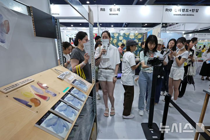 [서울=뉴시스] 박진희 기자 = '2025 서울국제도서전'이 열린 18일 서울 강남구 코엑스 행사장을 찾은 관람객들이 책갈피 굿즈를 살펴보고 있다. 올해 도서전에는 한국을 포함해 17개국의 530여 개 출판사와 출판 관련 단체 등이 참가한다. 2025.06.18. pak7130@newsis.com